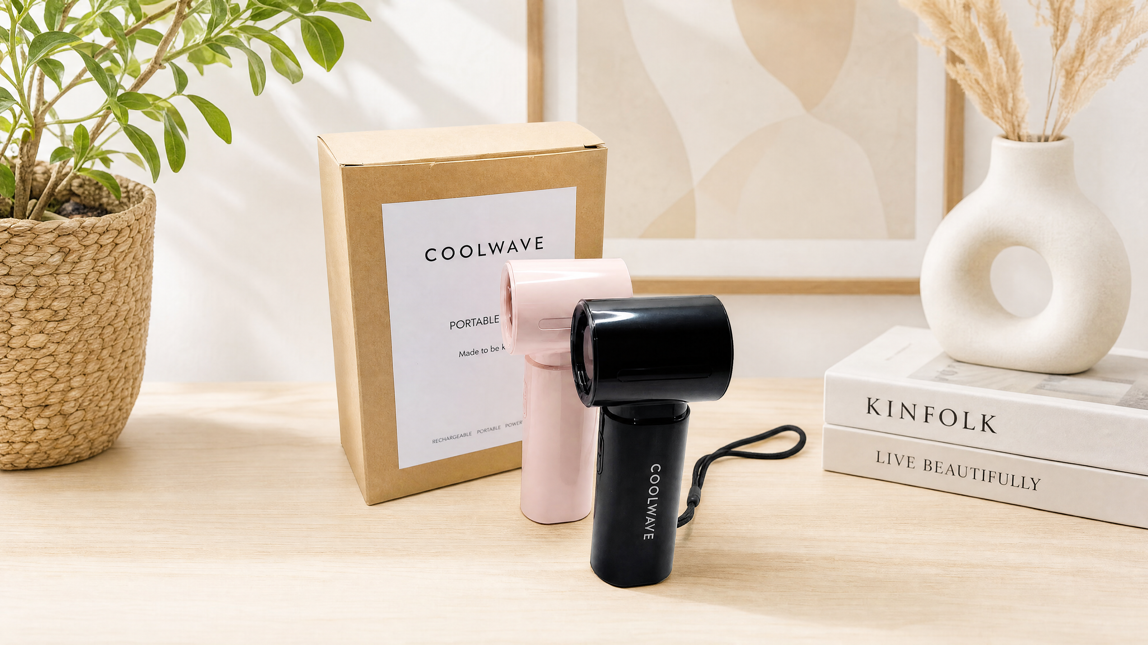 Pink and black CoolWave handheld fans displayed with branded packaging in a bright studio setting