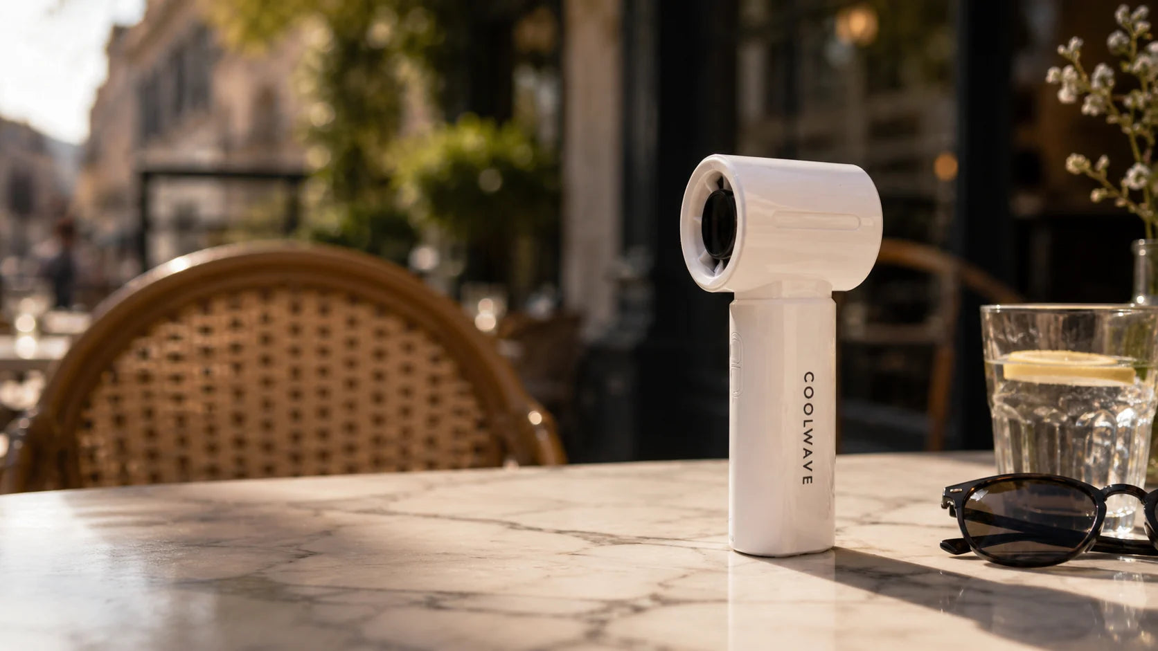 White CoolWave handheld fan on a sunlit café table