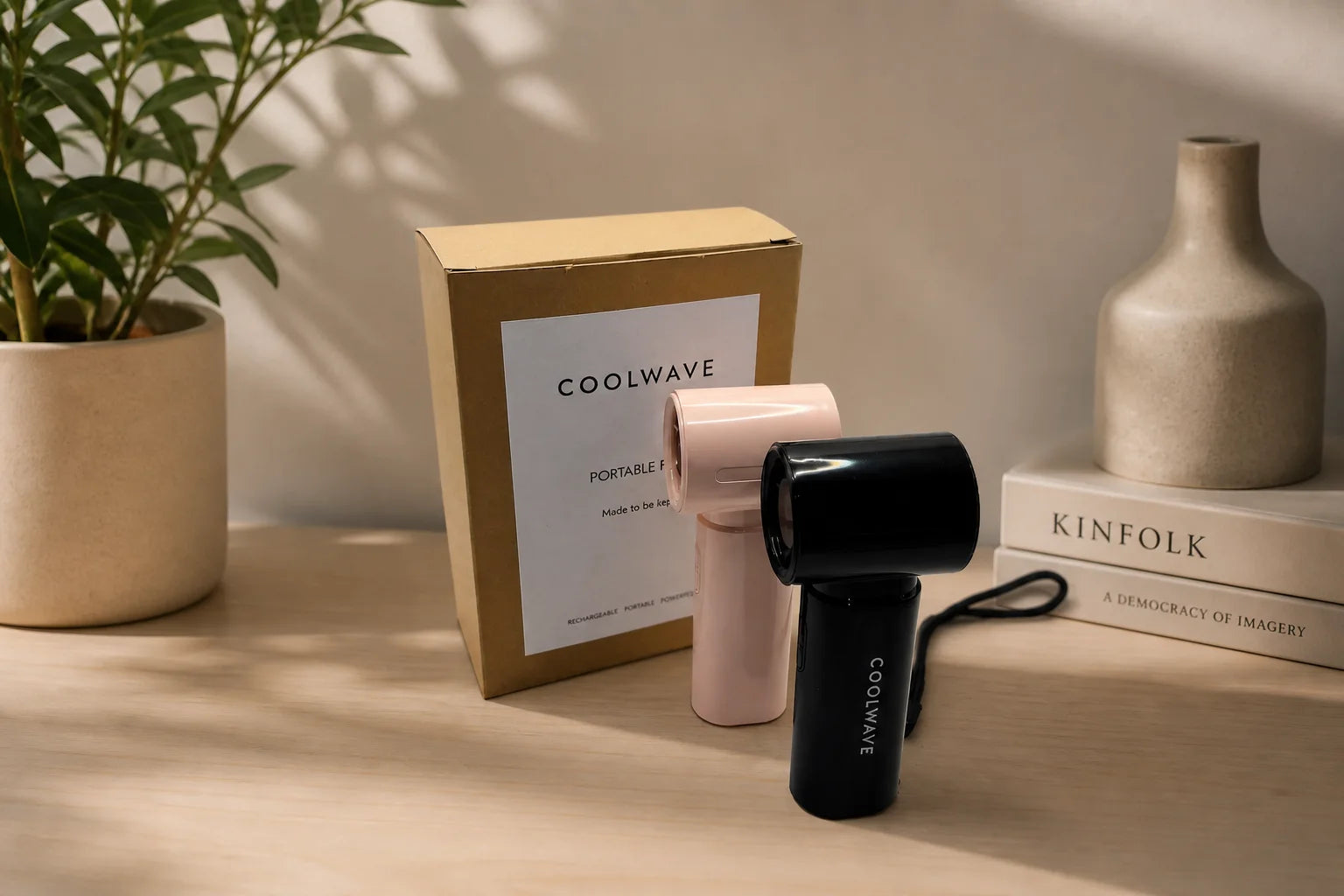 Pink and black CoolWave rechargeable handheld fans displayed with branded packaging